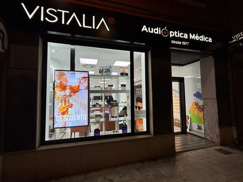 Fachada de Audióptica Médica de noche en Avenida Camí Nou 56, Xirivella: óptica y centro auditivo desde 1977